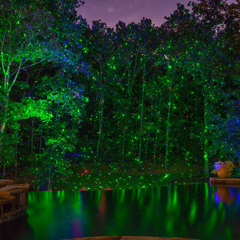 Laser lights illuminating a tree line.